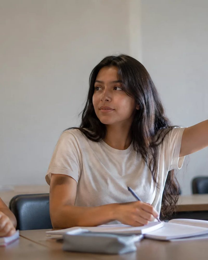 Dupla preparando uma rodada de debate, com cadernos e canetas espalhados na mesa